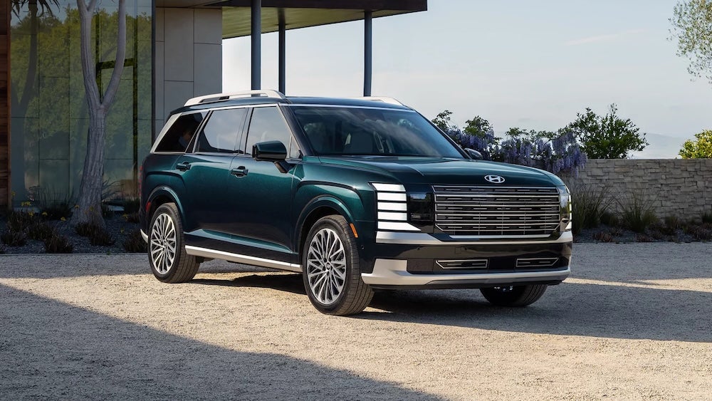 A dark green 2027 Hyundai Palisade SUV driving down a street