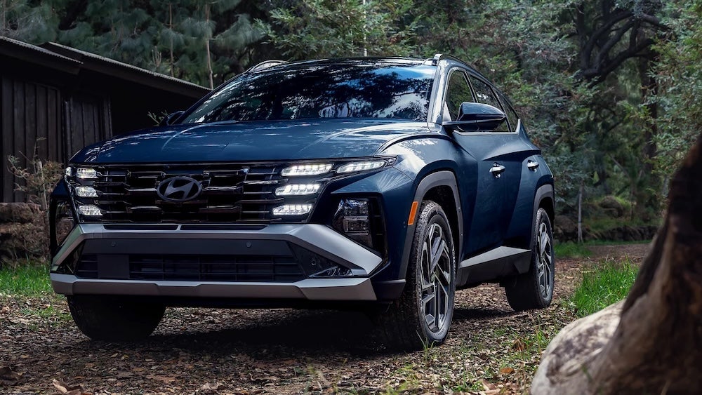 A dark blue 2026 Hyundai Tucson SUV parked near a cabin