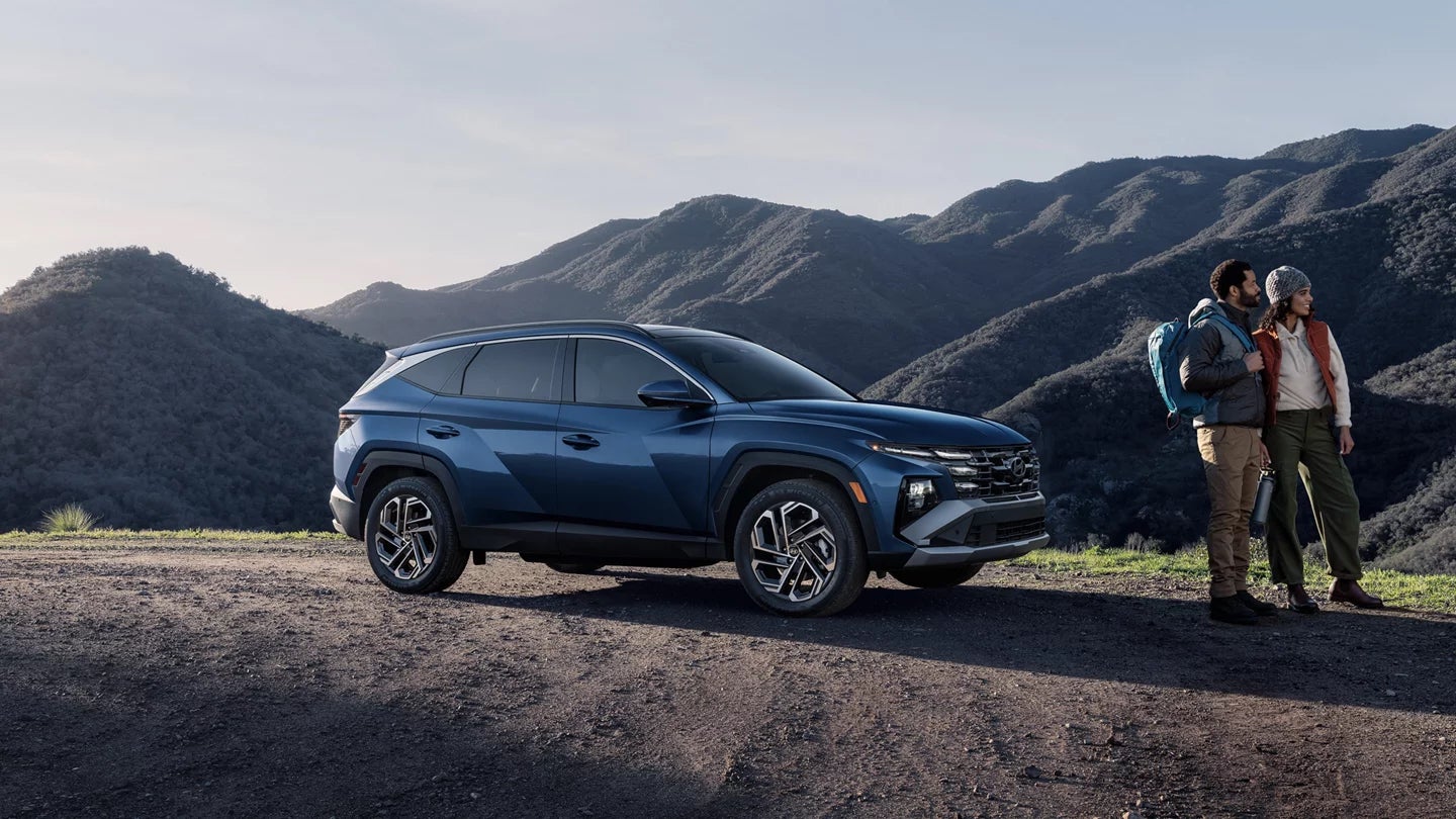 Two hikers standing beside a dark blue 2026 Hyundai Tucson SUV